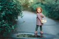 Little beautiful red-haired little girl standing near a puddle w Royalty Free Stock Photo