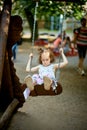 Little beautiful sad girl on swing with pensive face on the playground Royalty Free Stock Photo