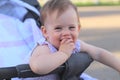 little, beautiful, smiling, cute redhead baby in a pram out-of-doors in a sleeveless shirt holding fingers in his mouth Royalty Free Stock Photo