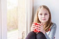 Little beauty girl with cup at the window Royalty Free Stock Photo