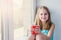 Little beauty girl with cup at the window Royalty Free Stock Photo