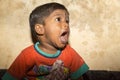 A little beggar boy from India standing on the streetside, crying for food.