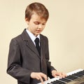 Little beginner musician in suit playing the electronic organ Royalty Free Stock Photo