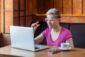 Little bit! Portrait of attractive young girl with short hair in pink t-shirt is sitting in cafe, working and making video call on Royalty Free Stock Photo