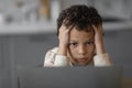 Little black boy feeling stressed and worried while looking at laptop screen, Royalty Free Stock Photo