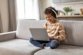 Little black boy wearing headphones using laptop computer at home Royalty Free Stock Photo