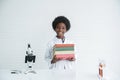 Little Black ten years old boy smile holding many text books with a microscope various colorful flasks test tube Royalty Free Stock Photo
