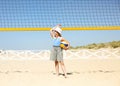 Little blond active girl plays volleyball on the beach with a ball Royalty Free Stock Photo