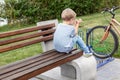 Little blond alone upset boy in casual jeans wear sitting on wooden bench in park. Lonely unhappy kid outdoors Royalty Free Stock Photo