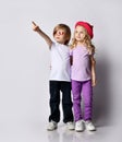 Little blond baby girl and boy in stylish clothing standing, hugging each other and pointing at something above Royalty Free Stock Photo