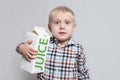 Little blond boy cuddles a large white carton juice package. Light background