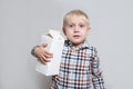 Little blond boy cuddles a large white carton package. Light background Royalty Free Stock Photo