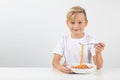 Little blond boy eats spaghetti and smiles Royalty Free Stock Photo