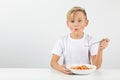 Little blond boy eats spaghetti and smiles Royalty Free Stock Photo