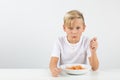 Little blond boy in front of white background eats spaghetti Royalty Free Stock Photo