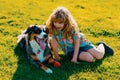 Little blond boy with her pet dog outdooors in park. Child with pet puppy dog. A child with a dog playing in nature on