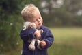 Little blond boy holding plush sheep in the nature Royalty Free Stock Photo