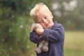 Little blond boy holding plush sheep in the park Royalty Free Stock Photo