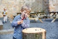 Little blond boy playing with hammer outdoors with brother.