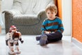 Little blond boy playing with robot toy at home, indoor. Royalty Free Stock Photo