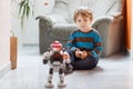 Little blond boy playing with robot toy at home, indoor. Royalty Free Stock Photo