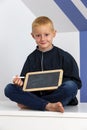 Little blond boy sitting with a chalk slate Royalty Free Stock Photo