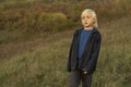 Little blond boy walks through clearing on warm autumn day. Child rests in fresh air in nature. Happy childhood