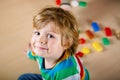 Little blond child playing with lots of colorful plastic blocks indoor. Kid boy wearing colorful shirt and having fun Royalty Free Stock Photo