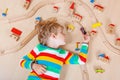 Little blond child playing with wooden railroad trains indoor Royalty Free Stock Photo
