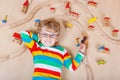 Little blond child playing with wooden railroad trains indoor Royalty Free Stock Photo