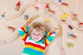 Little blond child playing with wooden railroad trains indoor Royalty Free Stock Photo