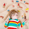 Little blond child playing with wooden railroad trains indoor Royalty Free Stock Photo