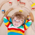 Little blond child playing with wooden railroad trains indoor Royalty Free Stock Photo