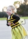 Little blond girl in bee costume dancing outdoors Royalty Free Stock Photo