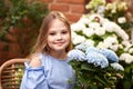 Little blond girl in blue dress with flowers nearby flowers store Royalty Free Stock Photo