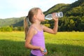 Little blond girl doing fitness exercises in the park and drinking a water Royalty Free Stock Photo