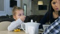 Little blond girl drinking tea sitting in cafe with her lovely parents.