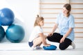Little blond girl exercising with her professional physician