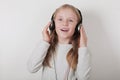 Blond girl with headphones listening music and singing. Cute little girl making a rock-n-roll sign. Royalty Free Stock Photo
