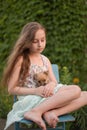 A little blond girl with her pet dog outdooors in park