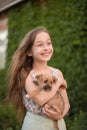 A little blond girl with her pet dog outdooors in park