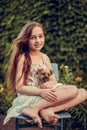 A little blond girl with her pet dog outdooors in park