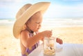 Little Blond Girl in Large Hat Drinks Juice with Spoon Royalty Free Stock Photo