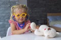 Little blond girl playing doctor with her toy bear and check heartbeat with stethoscope,leisure of european toddler Royalty Free Stock Photo