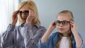 Little blond girl putting eyeglasses, wants to look like grandmother, family