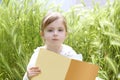 Little blond girl reading book green spikes garden Royalty Free Stock Photo