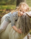 Little blond girl riding little horse pony and hugging it Royalty Free Stock Photo