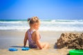 Little Blond Girl Sits by Sand Heap Plays on Beach