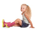 Little blond girl in skirt, blouse, rubber boots sitting isolated. Royalty Free Stock Photo