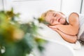 Little blond girl sleeping on white bed with her hands under her cheek. Carefree, childhood.